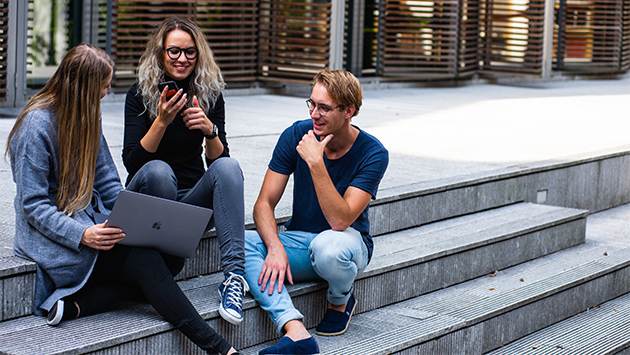 millennials gathered outside around laptop
