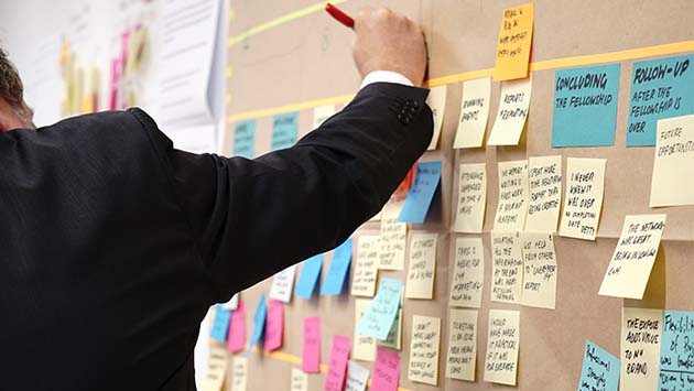 man writing on post-it notes on planning board